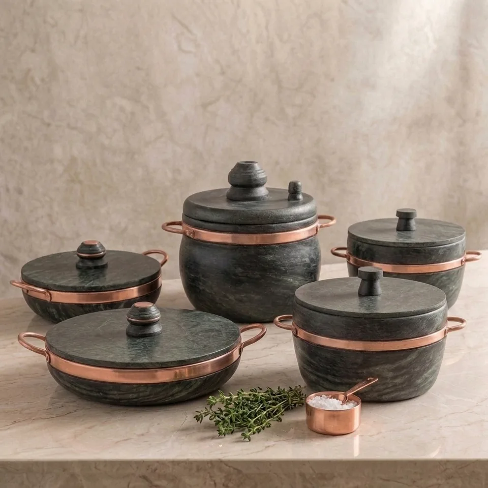 Conjunto de panelas de pedra sabão com alças de cobre sobre bancada de mármore